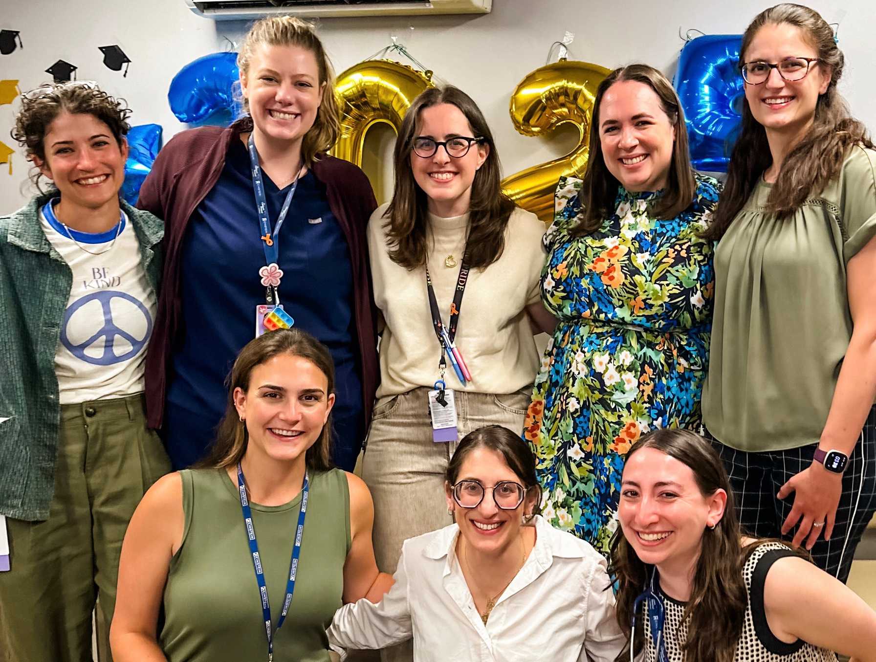 Team of healthcare professionals and staff posing in front of 2023 balloons at a celebratory indoor event.