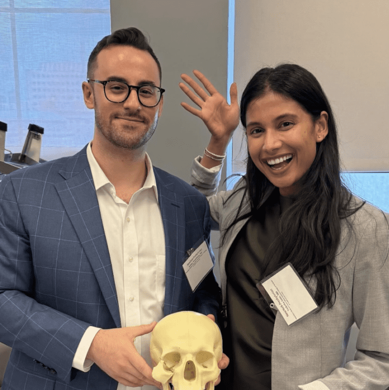 Two people holding a model of a skull