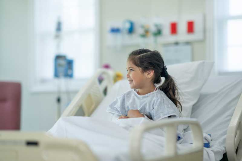 Girl sitting up and smiling in hospital bed