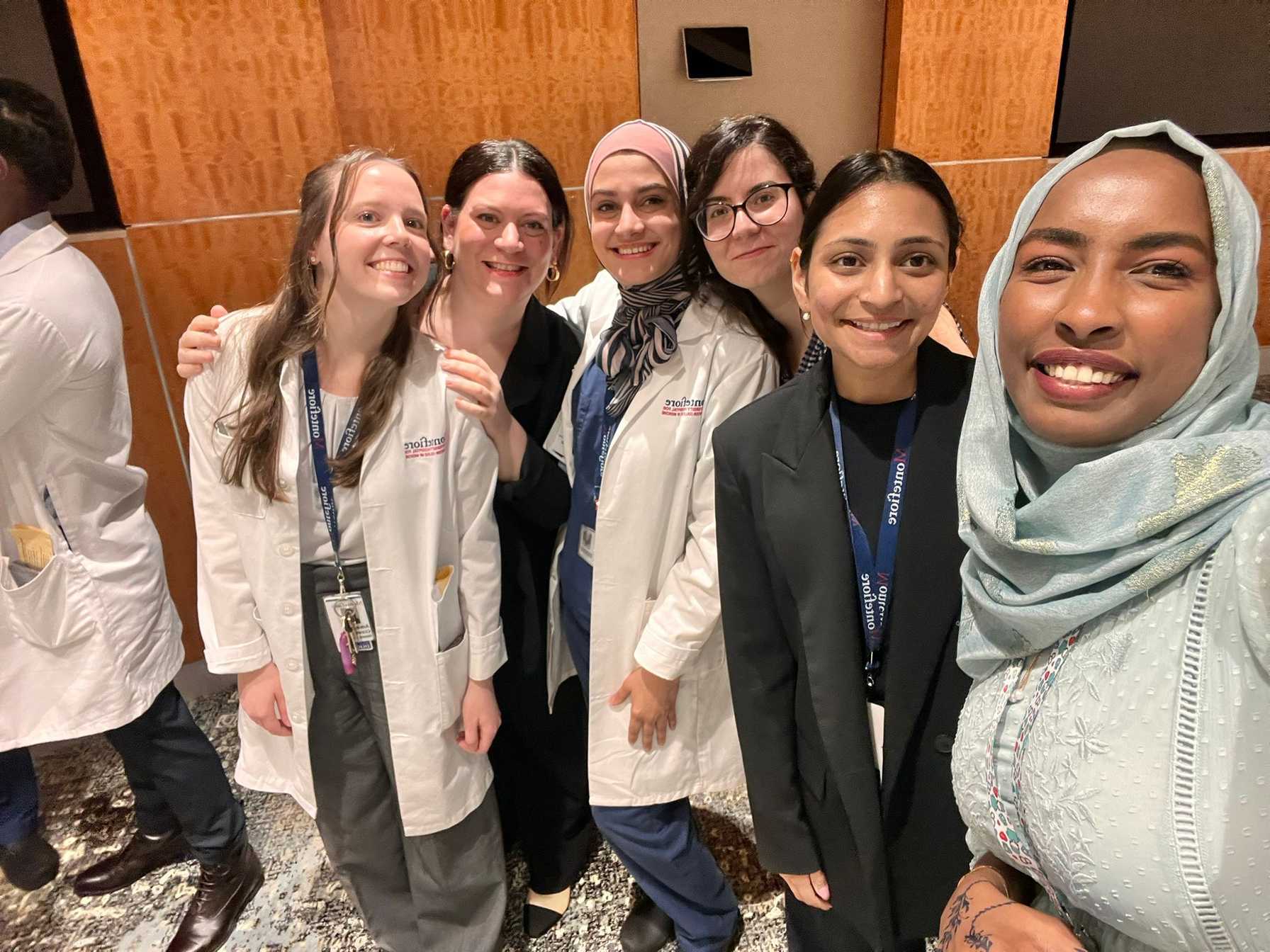 Group of smiling medical professionals, some in white coats and others in formal attire, posing together at a conference event.